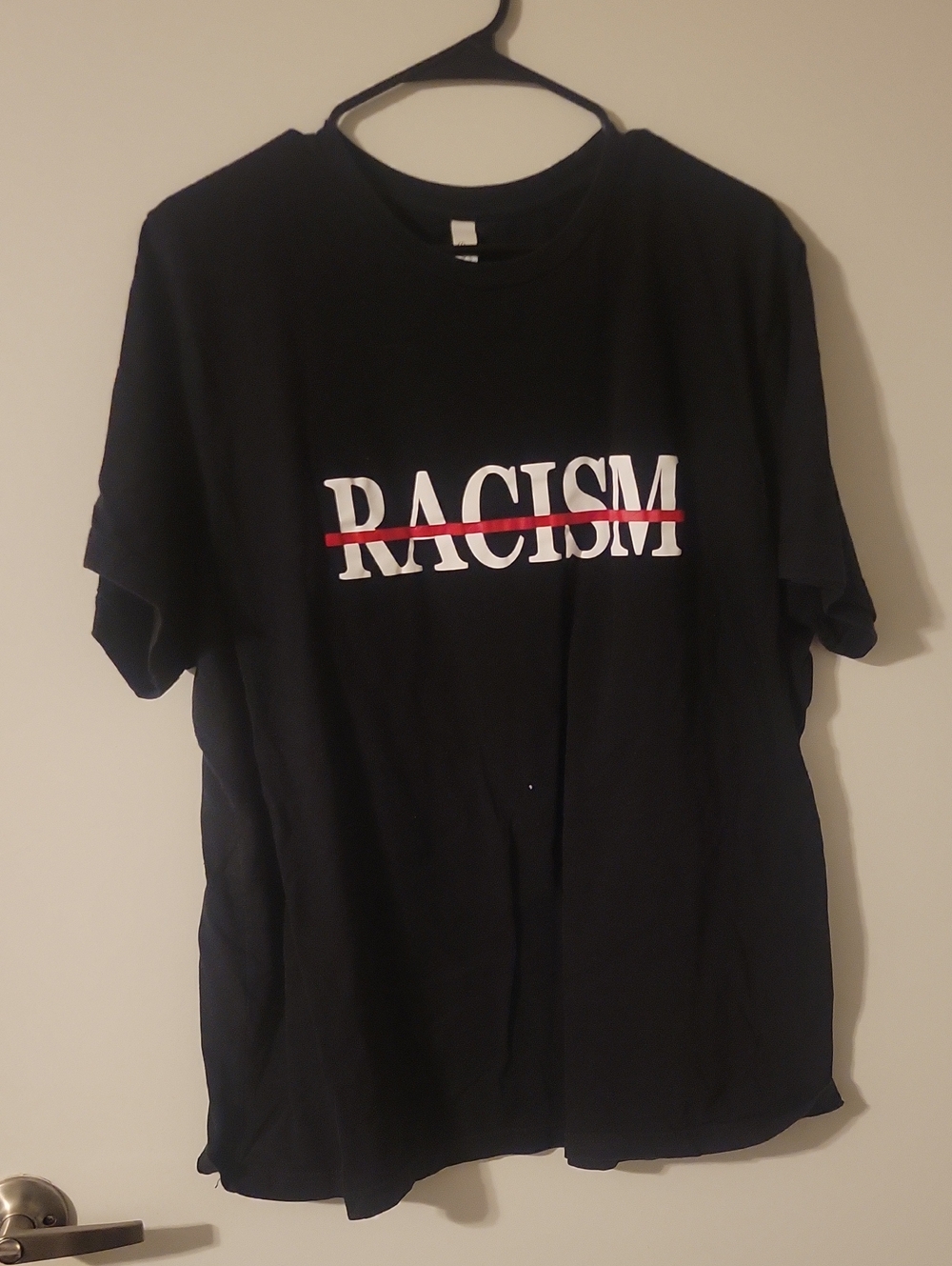 Black Graphic Tee with White "RACISM" Text and Red Strike